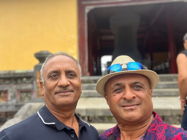 Two men posing in front of an architectural building.
