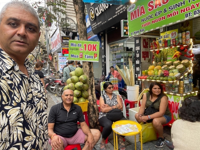 People sitting at a street market with stalls visible.