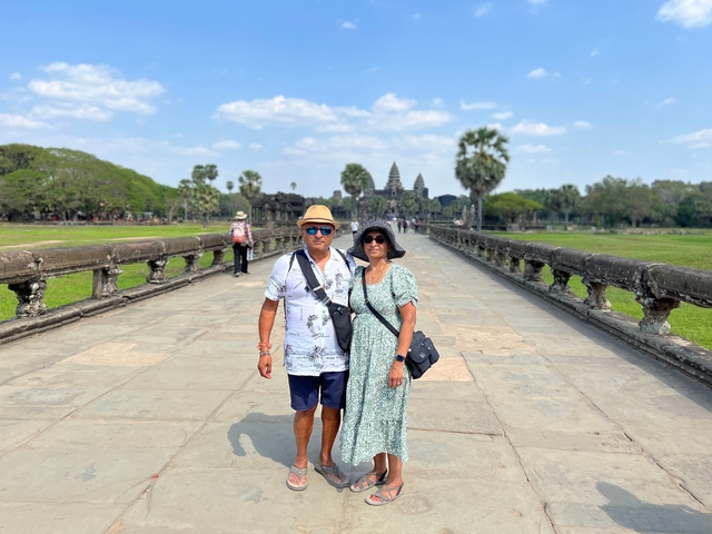 Couple posing on a stone pathway with Angkor Wat in the background.