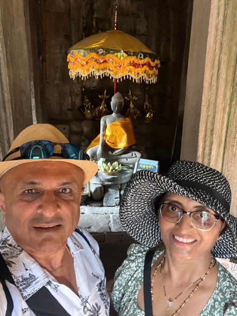 Man and woman posing in front of a Buddha statue.