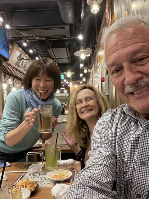 Group of people inside a restaurant setting, holding drinks and smiling.