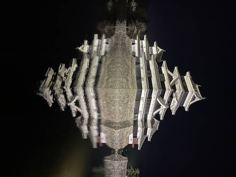 Reflection of a Japanese castle at night on still water.