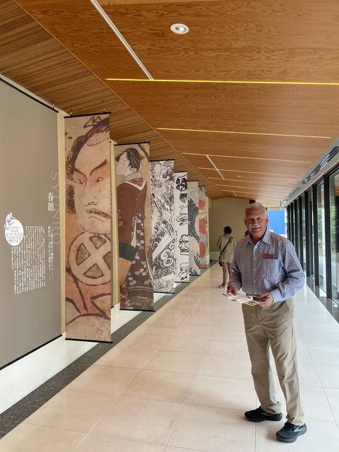 Person standing in an indoor space with art banners displayed on the wall.