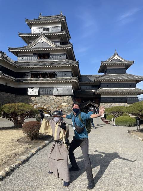 Man posing with a bicycle rack in front of a Japanese castle.
