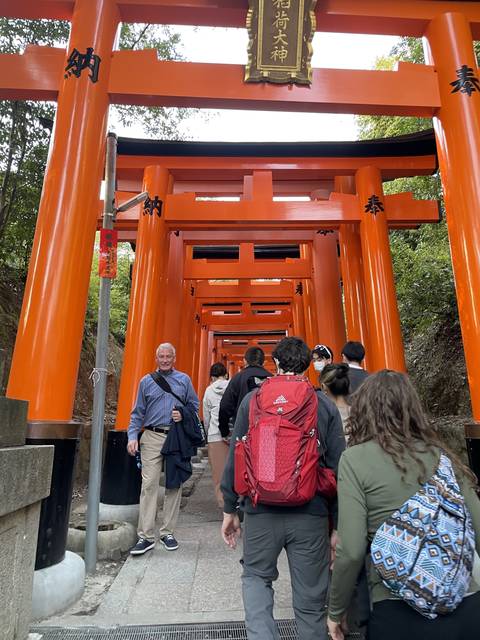 People walking through a Torii gate path in a Japanese shrine.