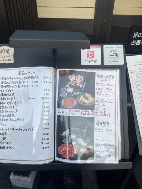 Restaurant menu with food images displayed outdoors.