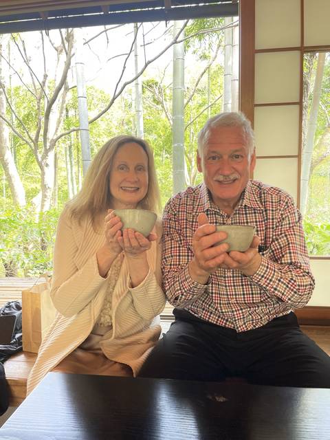Couple holding bowls of tea in a Japanese tea ceremony setting.
