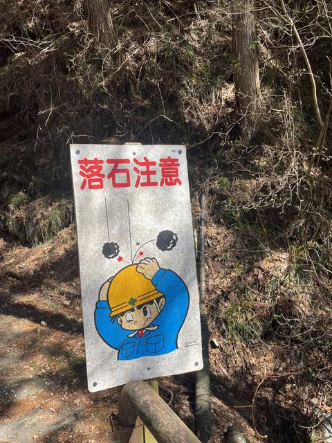 Cartoon safety sign in Japanese in a forest area.