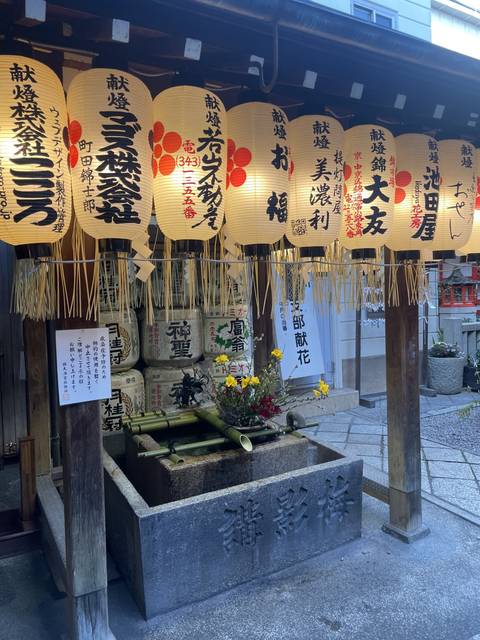 Decorative Japanese lanterns with text in front of a shrine.