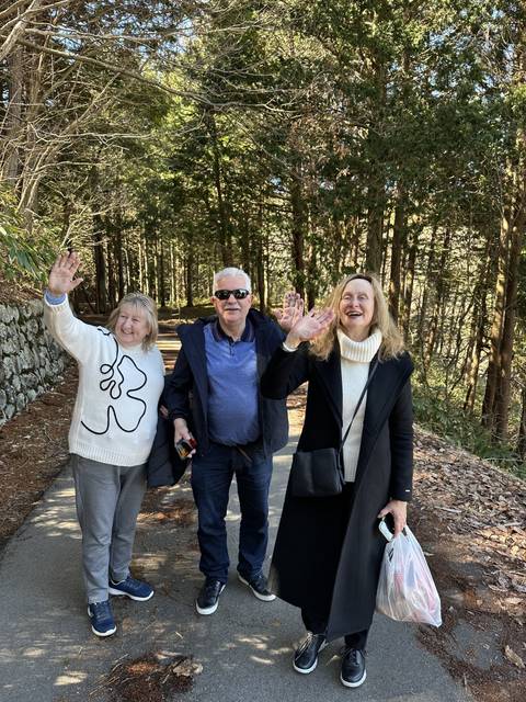 Three people posing happily in a forest path.