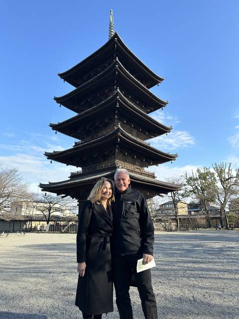Two people posing in front of a multi-tiered pagoda.