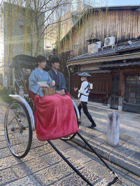 Two people in a traditional rickshaw on a stone path.