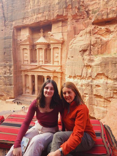 Two people sitting in front of Petra's iconic rock-cut architecture.