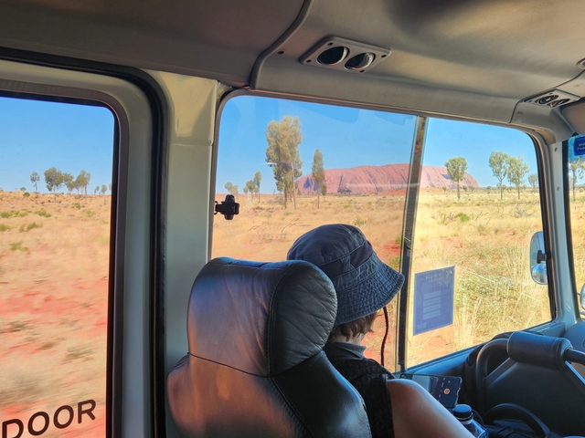 View of Uluru from inside a vehicle, through the window.