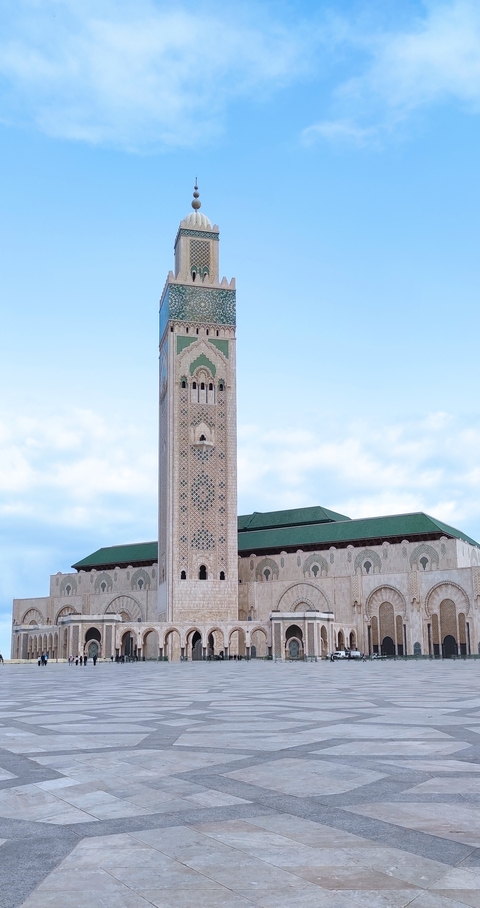 Tall mosque with a large minaret against a blue sky.