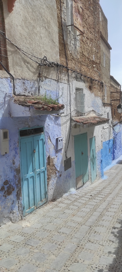 Narrow street with blue-painted walls and doors.