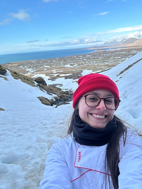 Person posing on a snowy hill with a view.