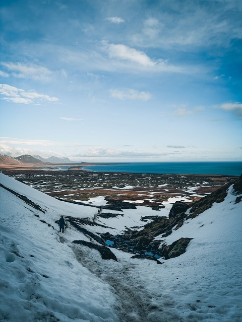 Snow-covered landscape with ocean view.