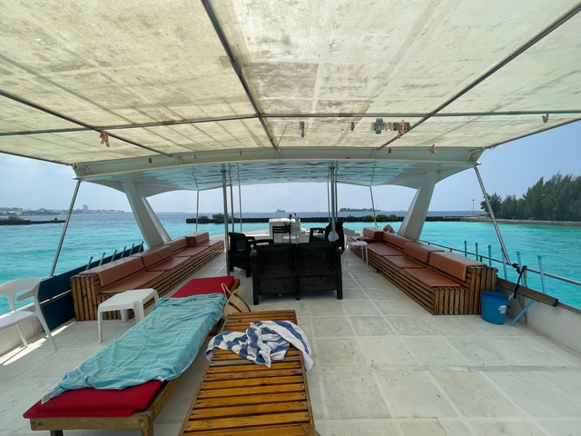 Interior of a boat with seating area looking out to the ocean.
