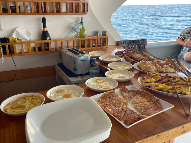 Breakfast buffet with eggs, pastries, and other dishes on a boat.