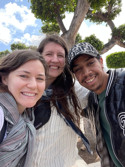 Group selfie of smiling people outdoors.