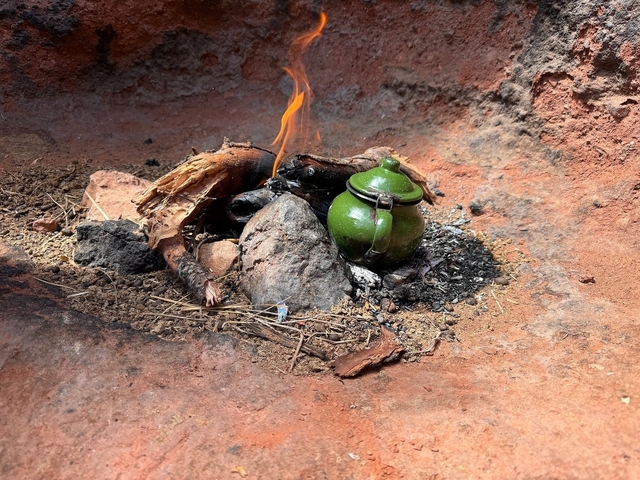 Tea pot with open fire in a rustic setting.