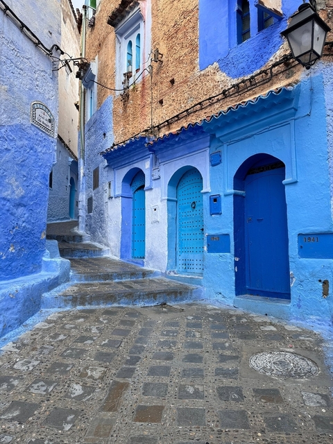 Blue-painted stone buildings lining narrow street.