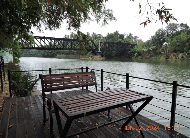 Bench with a river view and a metal bridge in the background