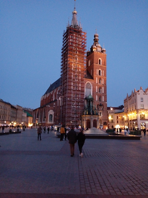 A building under scaffolding in a city square during twilight.
