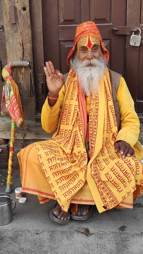 Person in traditional attire sitting with a staff.
