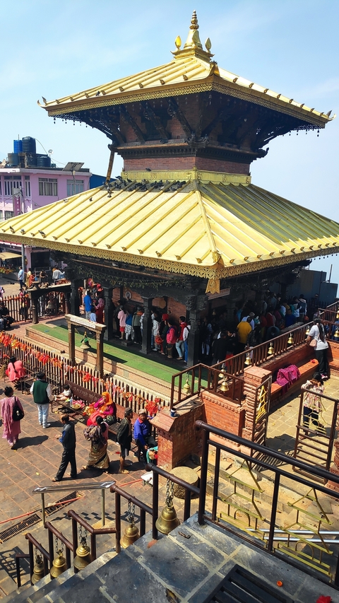 People queuing at a temple with a golden roof.
