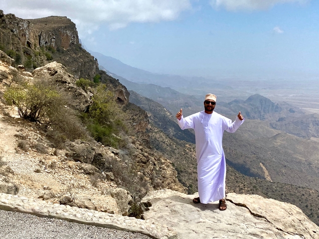Man standing on a mountain cliff with a scenic view.