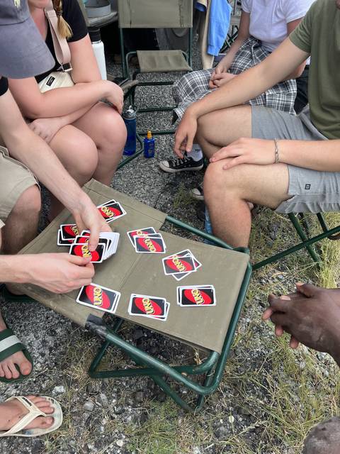 People sitting and playing cards at a campsite.