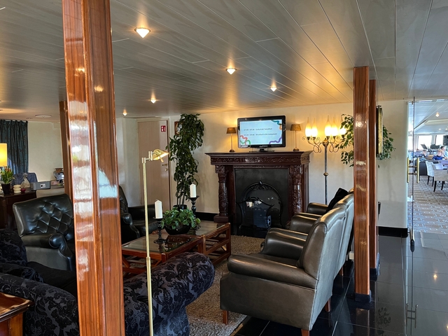 Another view of a ship's lounge with seating and a fireplace.