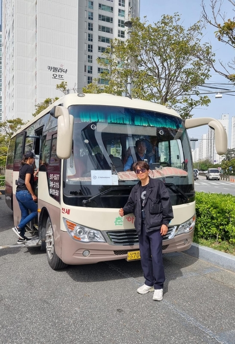 Man posing in front of a tour bus on a city street.