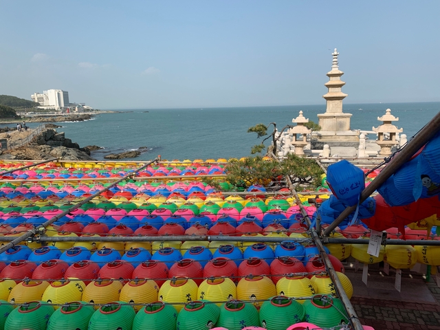 Seaside view with colorful lanterns and a pagoda.