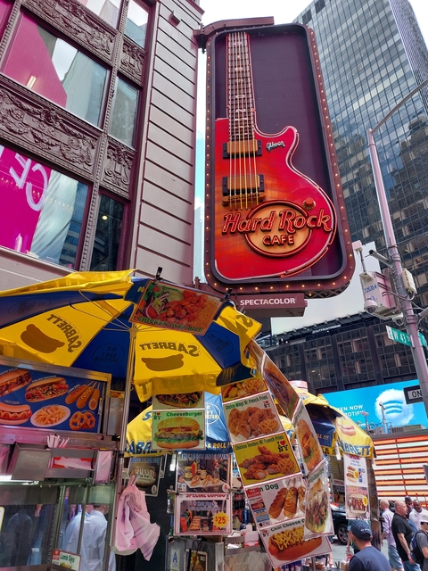Hard Rock Cafe sign on a street with food stalls.
