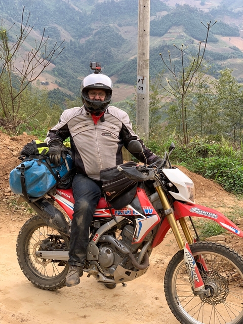 A man on a motorbike with a scenic background.