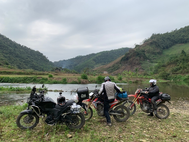 Motorcyclists by a river with a picturesque landscape.