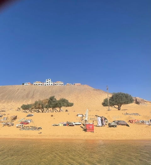 Desert hill with colorful buildings and trees at the base.