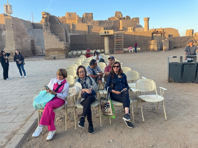 Group of people sitting on chairs in a historic site.