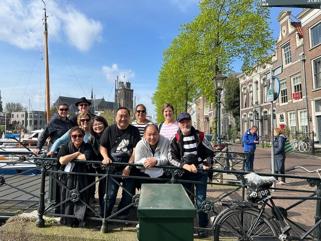 Group of tourists posing by a railing near historic European buildings.