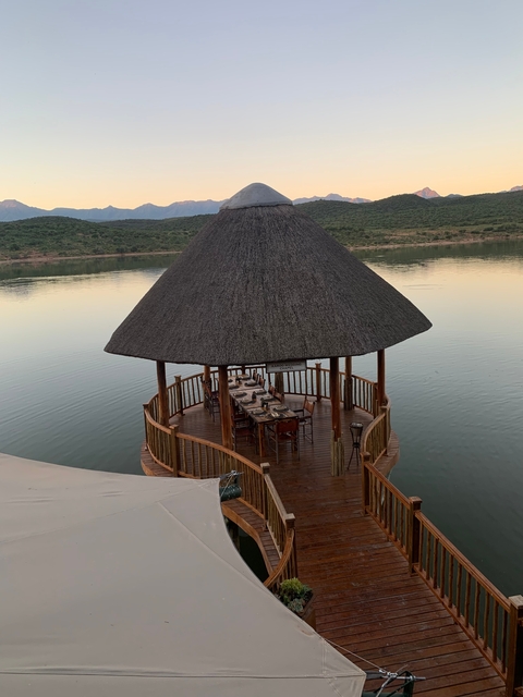 Gazebo over a lake with set dining tables.