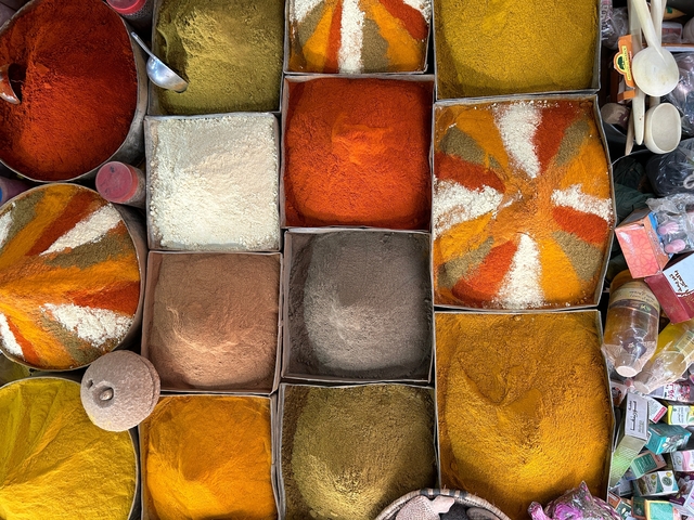 Colorful spices displayed in boxes at a market.