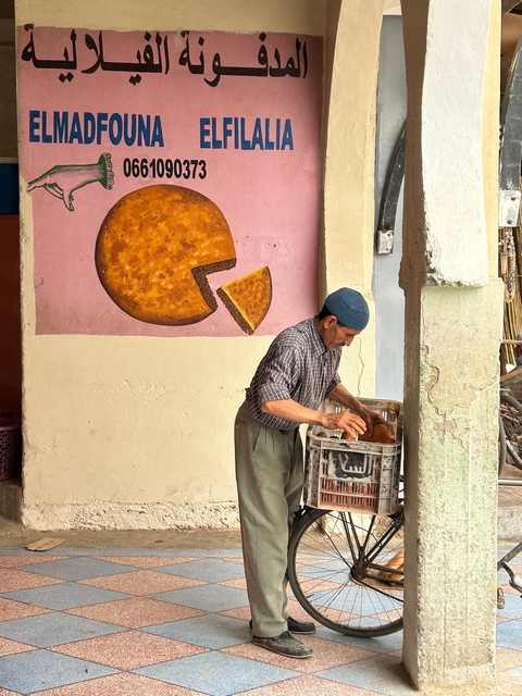 Man arranging goods with a mural painting of cheese.
