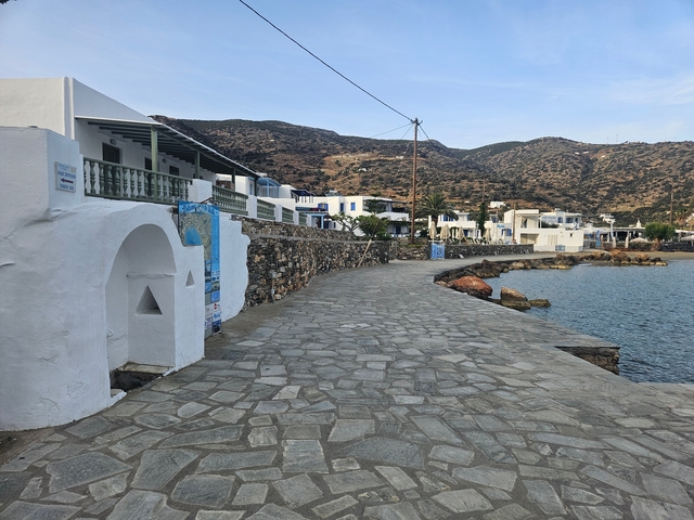 Coastal path with white buildings and mountains in the background.