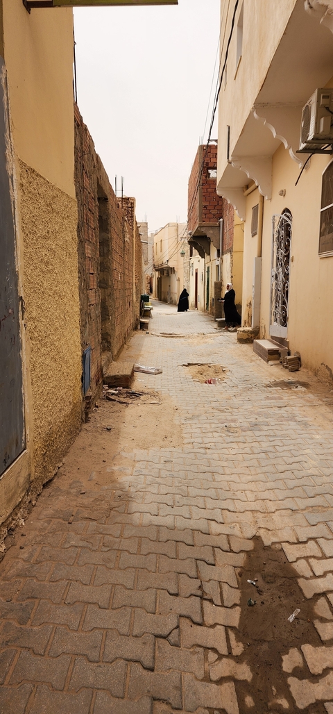 Narrow street with people in traditional clothing.