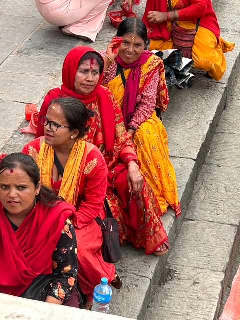 Women in vibrant traditional attire gathered on steps.