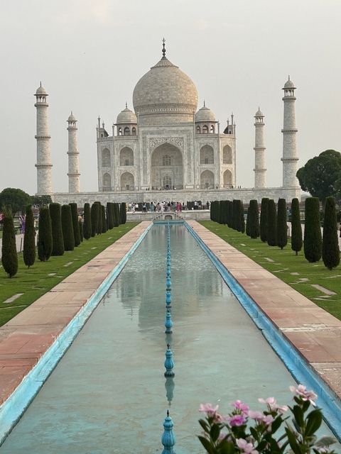 View of the Taj Mahal with reflecting pool and visitors.