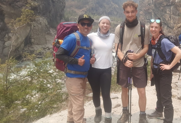 Group of hikers posing on a trail with mountainous landscape.